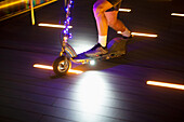 Man riding illuminated scooter