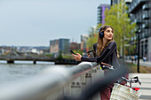 Young woman with smartphone at waterfront in city