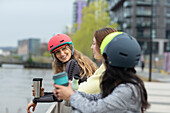 Young female friends with coffee talking in city