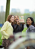 Happy young female friends celebrating birthday with cake