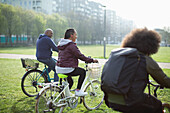 Happy family riding bicycles in sunny urban park