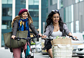Happy young female friends riding bicycles in city