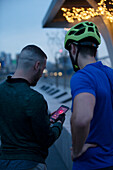 Men with bike helmet using smartphone at night