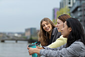 Happy young female friends talking with coffee in city