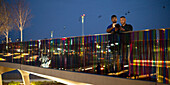 Men with smartphone on footbridge in city at night