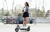 Young woman riding electric scooter in city