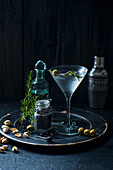 Martini-Cocktail mit Rosmarin, Oliven und Pistazien