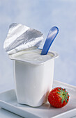 An opened yoghurt pot, with a strawberry