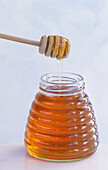 A glass of honey, with a honey dipper