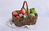 Basket with red and green apples and apple blossoms