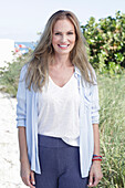 Long-haired woman in spring-like blue and white outfit on the beach