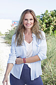 Langhaarige Frau in frühlingshaftem blau-weißem Outfit am Strand