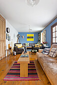 Living room with leather furniture, wooden floor and blue walls