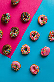 Donuts with icing and sugar sprinkles on a two-coloured base