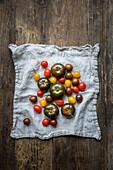 Mixed varieties of tomatoes on a linen tea-towel, on a wooden surface