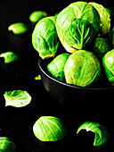 Brussels sprouts in a black bowl (Close Up)
