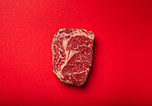 Rohes Ribeye-Steak auf rotem Hintergrund
