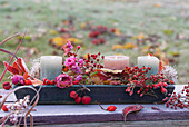 Autumn table decoration with foliage, candles, roses and rose hips