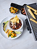 Five bean chili-con-carne with grilled corn and pumpkin guacamole, cooked on a raclette