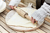 Making dough on a wooden board with a rolling pin outdoors