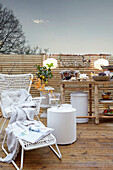 Terrace with white rattan furniture and wooden outdoor table
