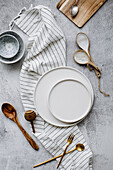 White plates, small bowls, cutlery, and striped linen napkin