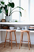 Window sill with wooden bar stools and monstera plant by the window