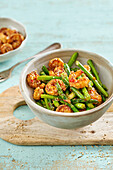 Fried shrimp with green asparagus, chili flakes, and sesame seeds