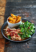 Pulled chicken with BBQ sauce, potato wedges and lamb's lettuce