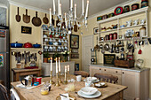 Country-style kitchen with covered wooden table and lots of hanging kitchen utensils