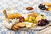 Cheese board with crackers, nuts and grapes