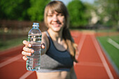 Sportswoman offering bottle of water