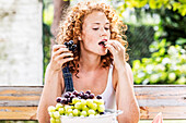 Porträt einer rothaarigen jungen Frau, die Trauben isst