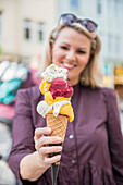 Woman holding ice cream cone with various sorts of ice cream