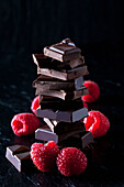 Pile of chocolate pieces and raspberries on black slate