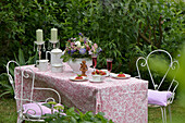 Romantisch gedeckte Kaffeetafel im Mai, mit Wiesenblumenstrauß, Sekt, Erdbeeren, Erdbeertörtchen und Kaffeegeschirr