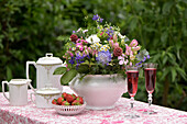 Romantisch gedeckte Kaffeetafel im Mai, mit Wiesenblumenstrauß, Sekt, Erdbeeren und Kaffeegeschirr