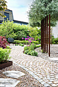 Path of paving stones in the garden with flower beds and gravel areas