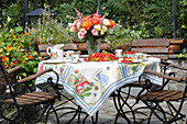 Sommertisch mit DIY-Tischdecke, Blumenstrauß, Erdbeerkuchen und Kaffeegeschirr