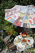 DIY-Sonnenschirm über Gartentisch mit Blumenstrauß und Erdbeerkuchen