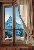 Blick auf den Matterhorn-Gipfel durch ein Fenster mit rustikalem Holzrahmen