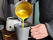Golden milk being poured into a mug