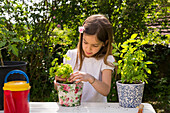 Kleines Mädchen Blumenerde Petersilie auf dem Tisch im Garten