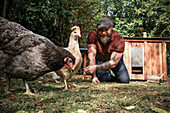 Man in his own garden, man feeding free range chickens