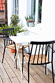 Small balcony table with black chairs and potted plants