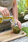 Johanniskraut in einem Apothekerglas mit Olivenöl auffüllen