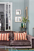 Sofa with velvet cover and cushions in the living room, in the background open glass door