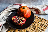 Ripe pomegranate fruit in black ceramic bowl