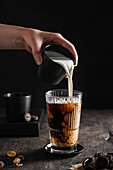 Milk being poured into iced coffee