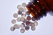 Aspirin tablets spilling from an open bottle